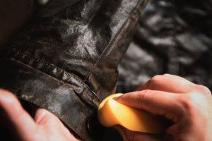 Close-up of wax treatment being worked into the fabric of a waxed cotton jacket.