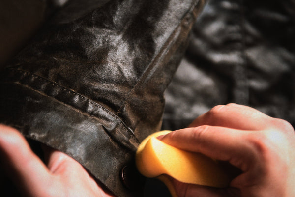 Close-up of wax treatment being worked into the fabric of a waxed cotton jacket.
