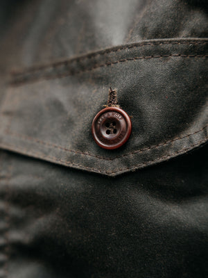 Close-up of corozo button, stitching and waxed cotton fabric on the Cairn overshirt in Raven