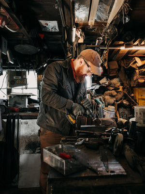 Cairn British-made waxed cotton overshirt in Raven worn by a blacksmith working at Flett Forge