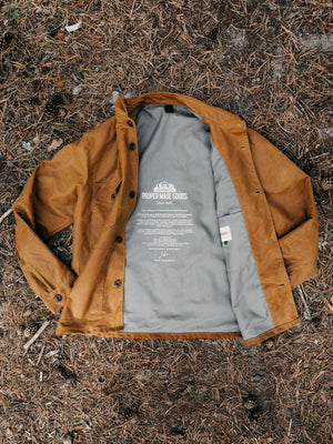 Cairn British-made waxed cotton overshirt in Whisky laid open showing the interior lining and printed label