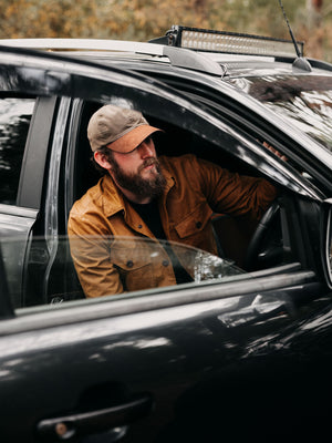 Cairn British-made waxed cotton overshirt in Whisky worn outdoors beside a 4x4