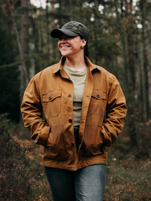 Cairn British-made waxed cotton overshirt in Whisky worn by a woman outdoors in Scottish woodland