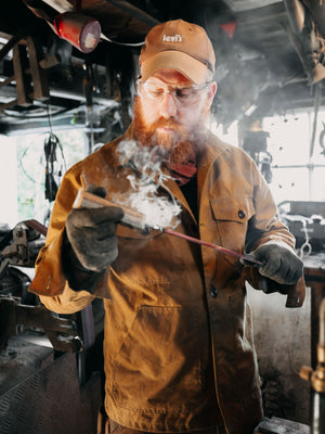 Cairn British-made waxed cotton overshirt in Whisky worn by a blacksmith working at Flett Forge