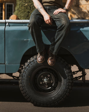 Bear&Wolf Founder Jake Green wearing his warn in pair of Brae Boots whilst sitting on the side of a classic Series 2 Land Rover in the Cotswolds. 