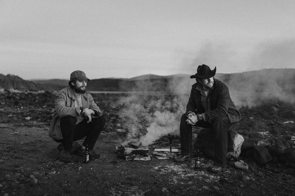 Bear&Wolf founders Jake and Bill sat either side of a small campfire in the Scottish Highlands, shot in black and white.
