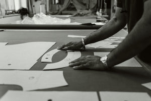 A black and white photograph showing a person's hands as they lay out paper pattern pieces to trace onto Halley Stevensons Waxed Cotton to make the Bear&Wolf Stac in the UK.