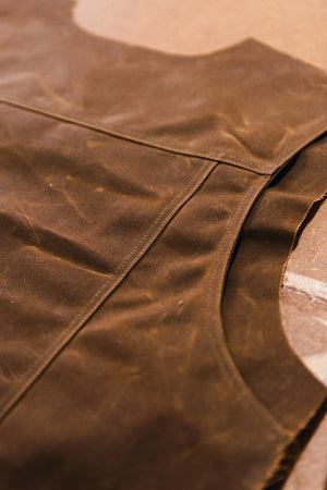 A close-up of a stac in saddle brown at the manufacturer, showing the waxed cotton fabric and stitched seams.
