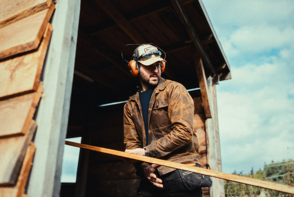 A logger operating heavy wood work machinery whilst wearing a Stac in saddle brown and safety gear at a timber yard.
