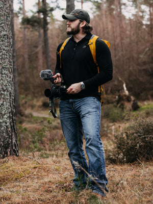 Bear&Wolf founder Jake wearing the Traverse Shirt and Wax Cap in a forest in Scotland.