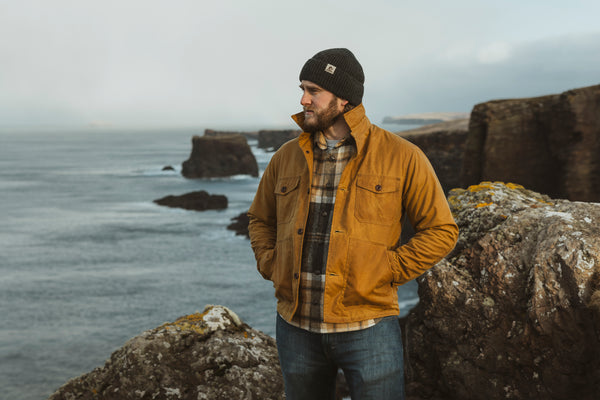 Bear&Wolf founder Jake wearing the Cairn Overshirt and Lambswool Beanie on the Shetland coast.