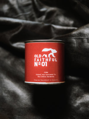 Overhead product photograph of a 250ml tin of Old Faithful No.01 annual wax treatment resting on the freshly reproofed waxed cotton fabric of a Cairn Overshirt.
