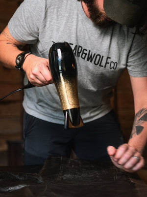 Using a hair dryer to gently heat Old Faithful No.01 wax treatment on a Cairn Overshirt, helping the wax absorb into the cotton fabric before removing any excess.