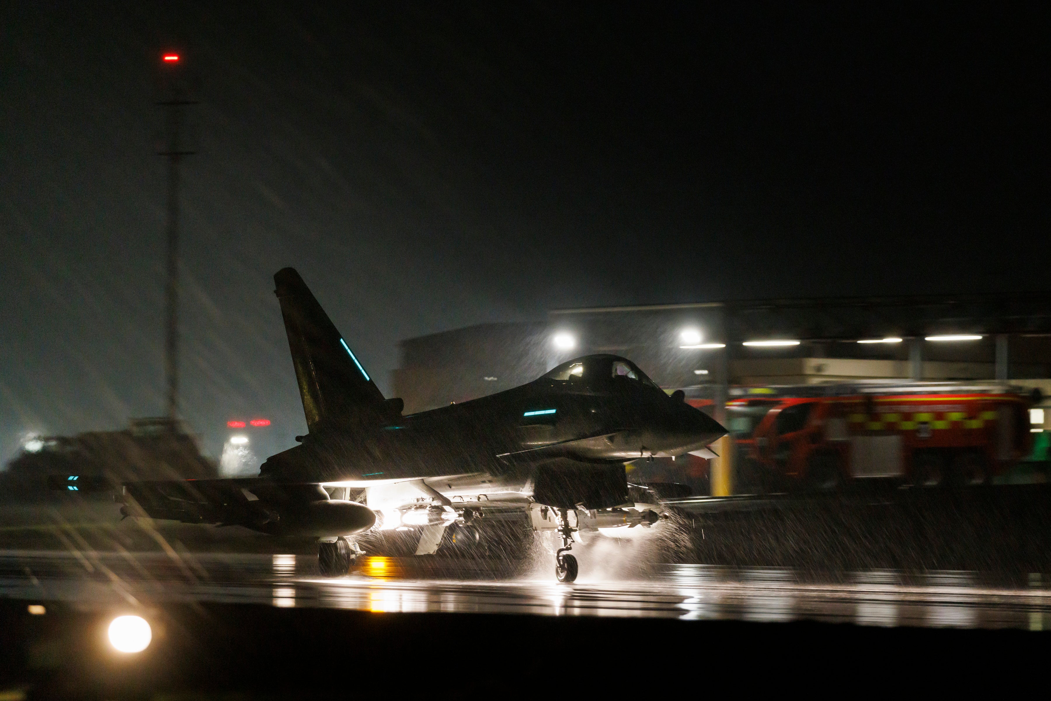 RAF Typhoon fighter jet on a wet flight line during night operations at RAF Akrotiri in Cyprus