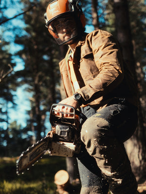 Man wearing The Stac heavyweight wax jacket while working with a chainsaw at Moore Timber Co.